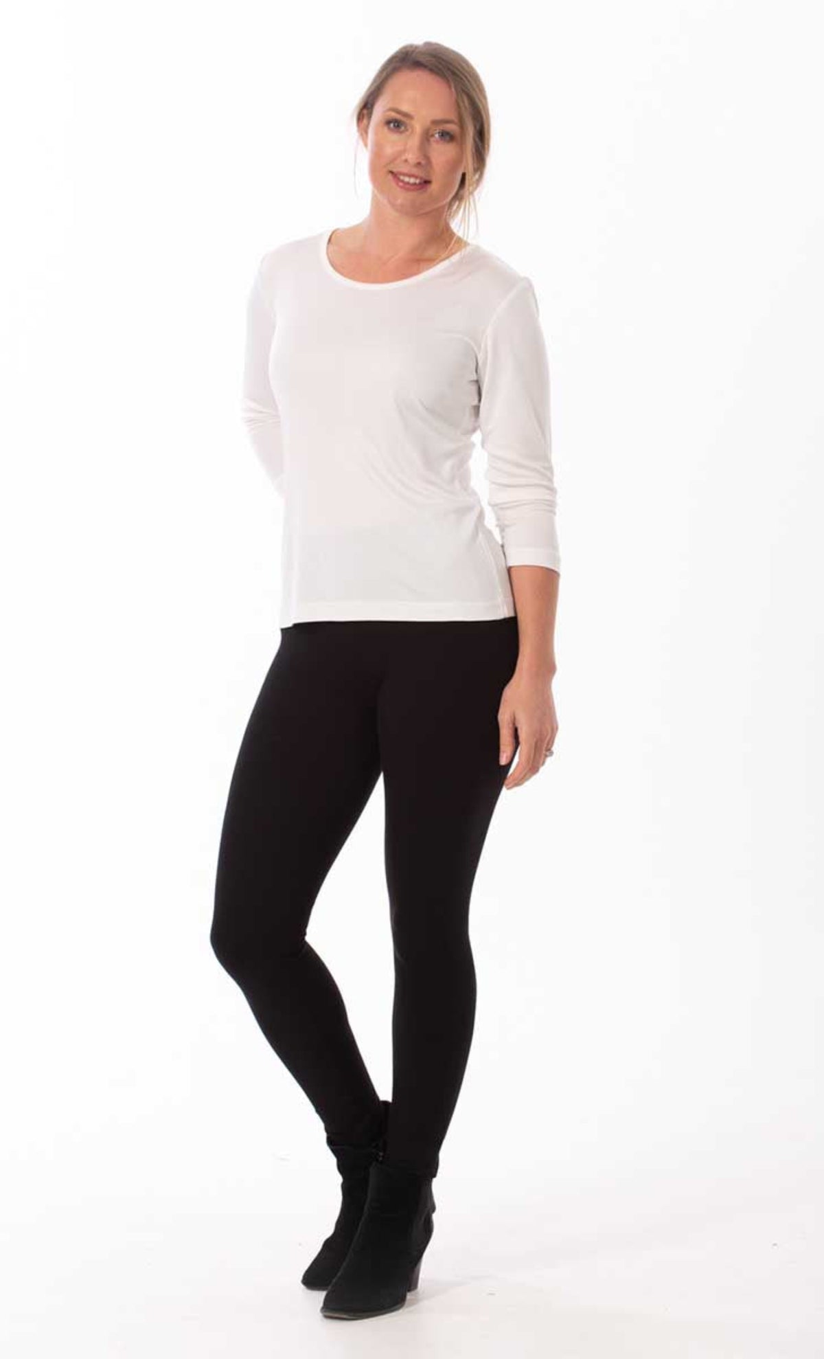 Woman wearing a silk white long-sleeve top and black leggings on a white background