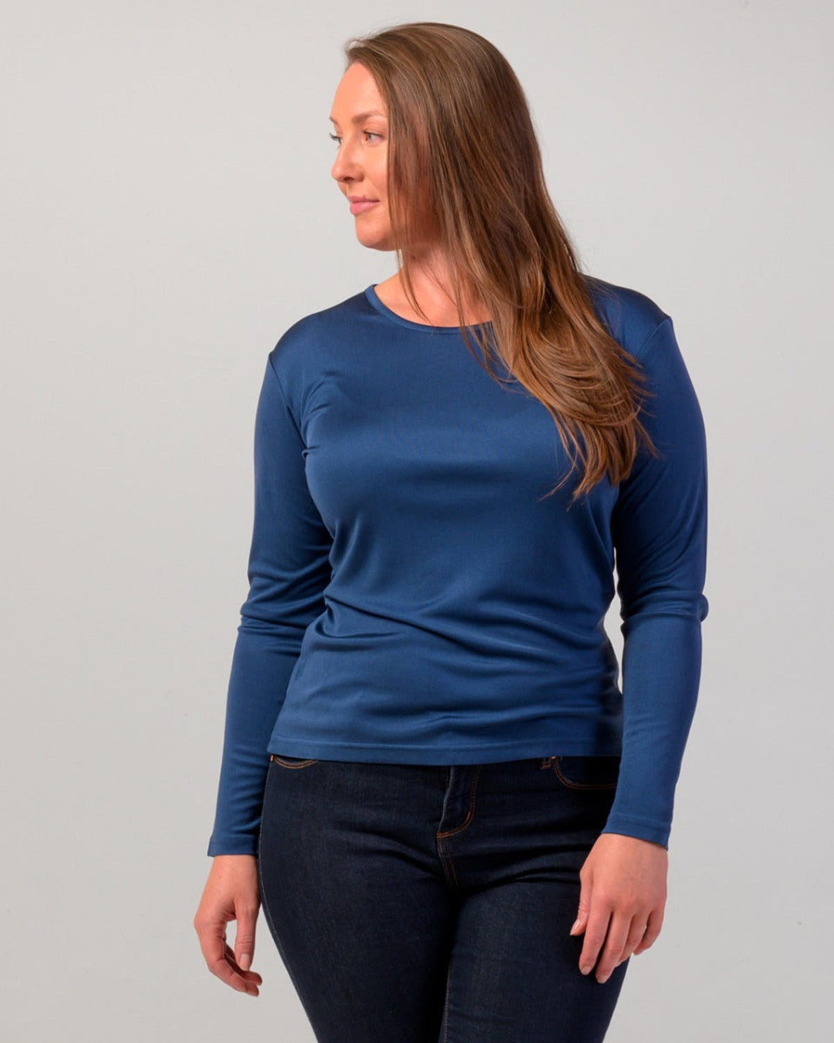 Woman wearing a silk blue long-sleeve shirt against a gray background
