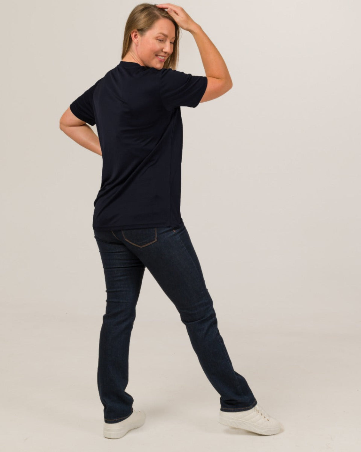 women wearing black vee neck silk  t-shirt and jeans on a plain background