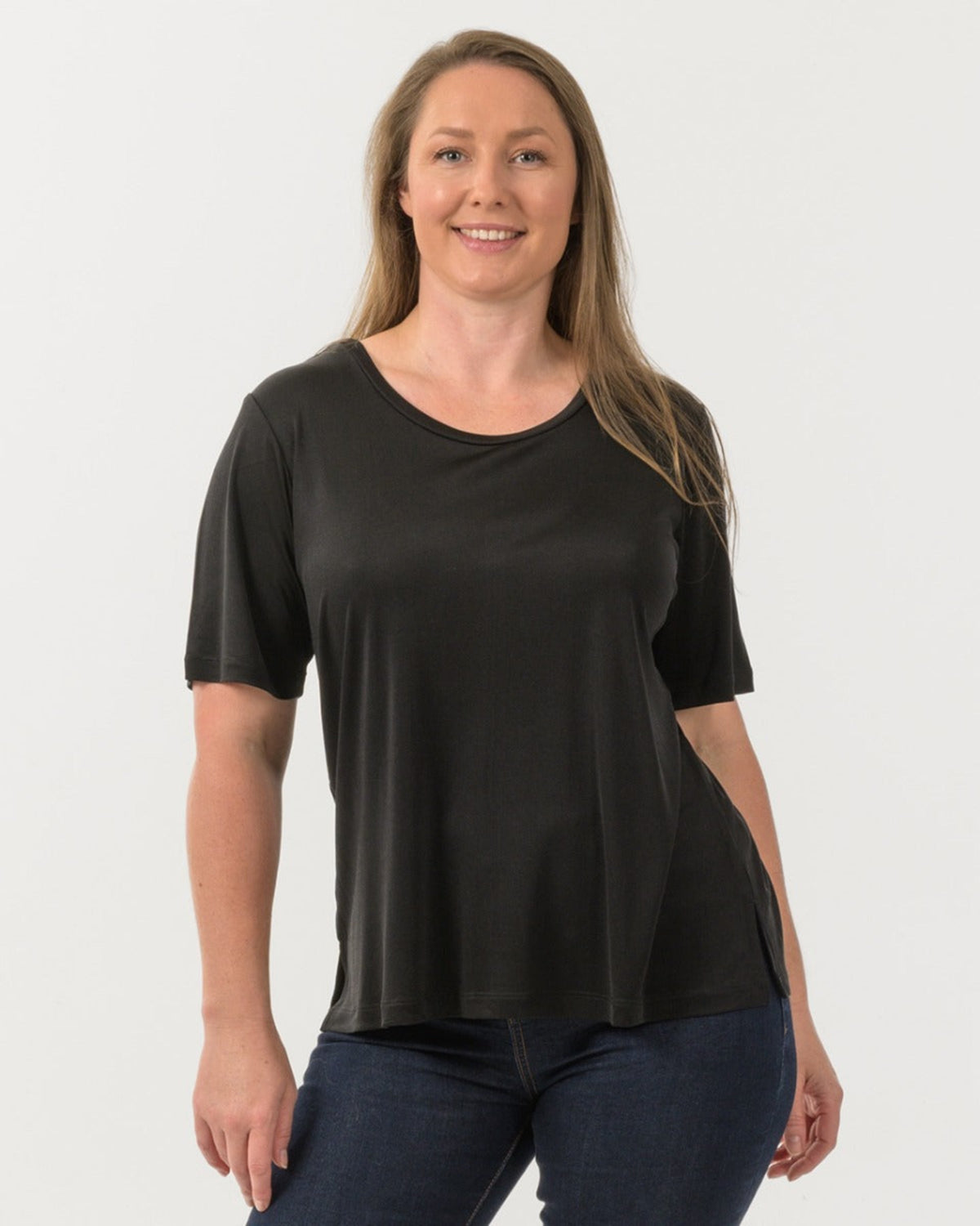 Woman wearing a black silk t-shirt and blue jeans on a white background