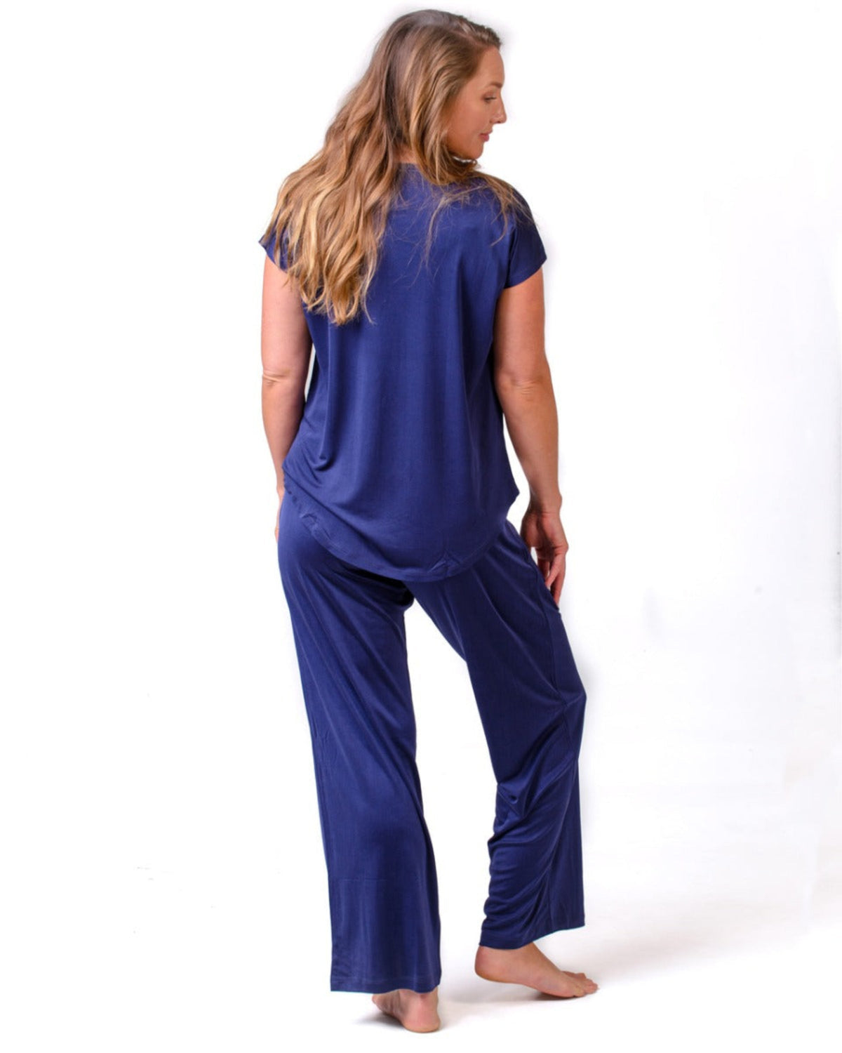 Woman wearing a silk  blue pajama set on a white background