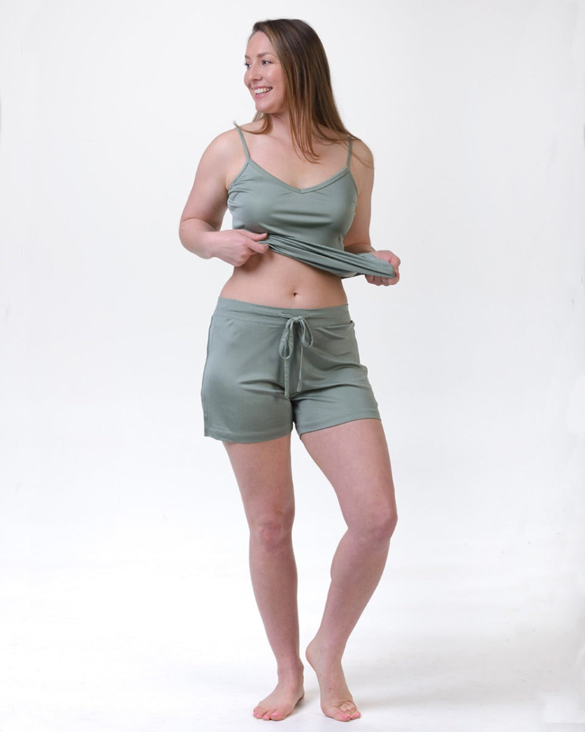 Woman wearing a sage cami silk top and silk shorties 