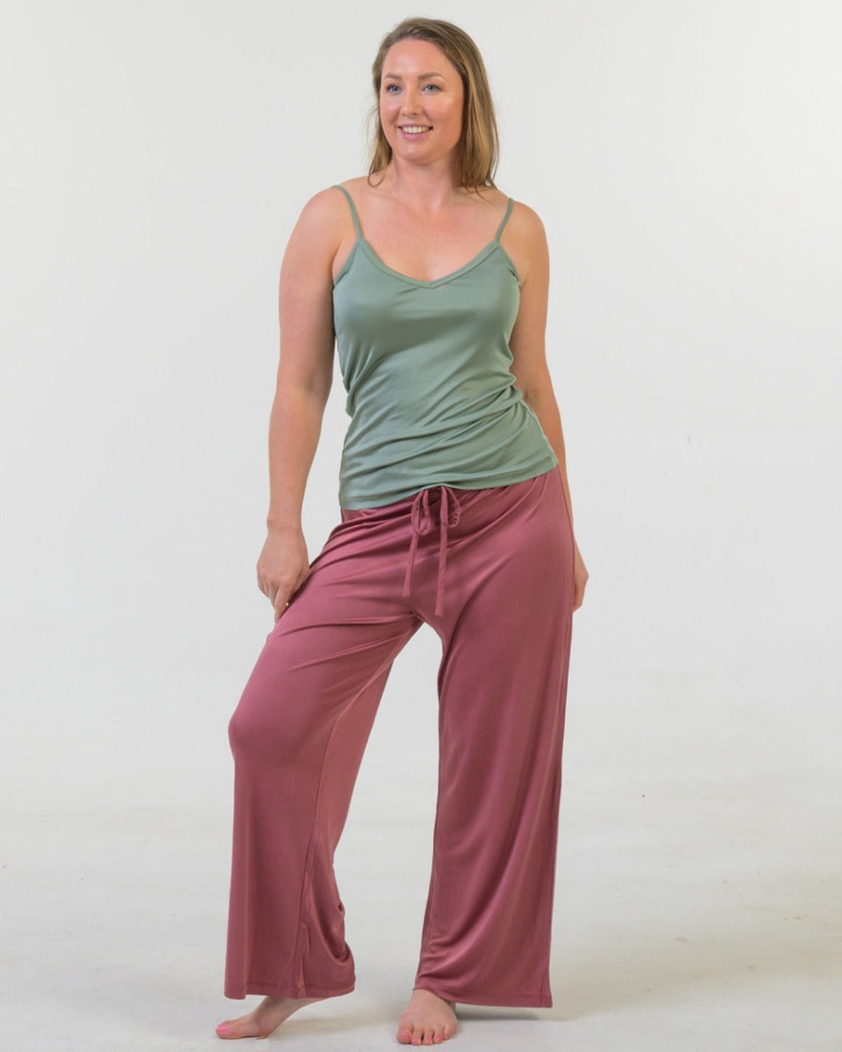 Woman wearing a sage  tank top and silk long pants pink pants