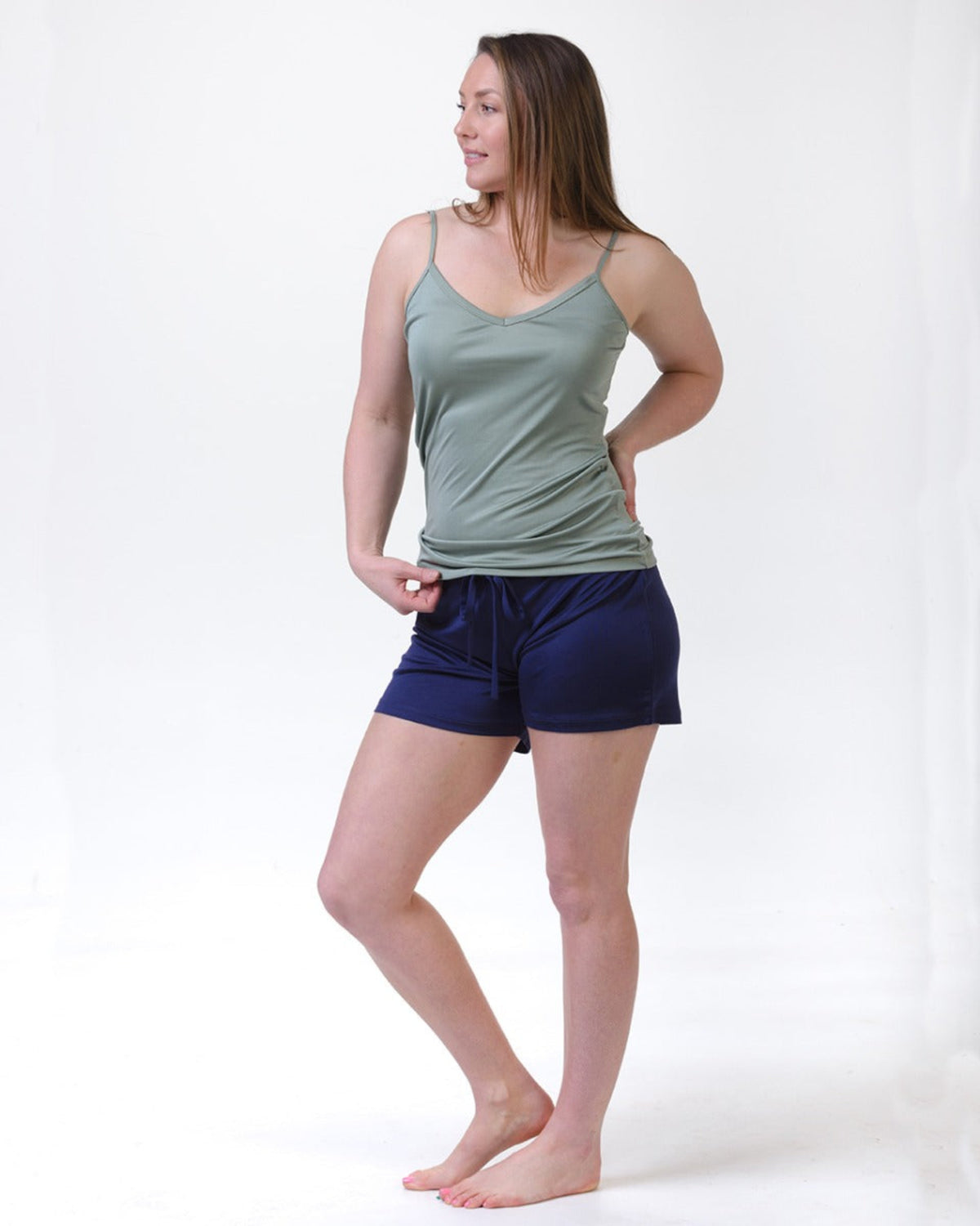 Woman wearing a silk sage  tank top and silk navy shorties 