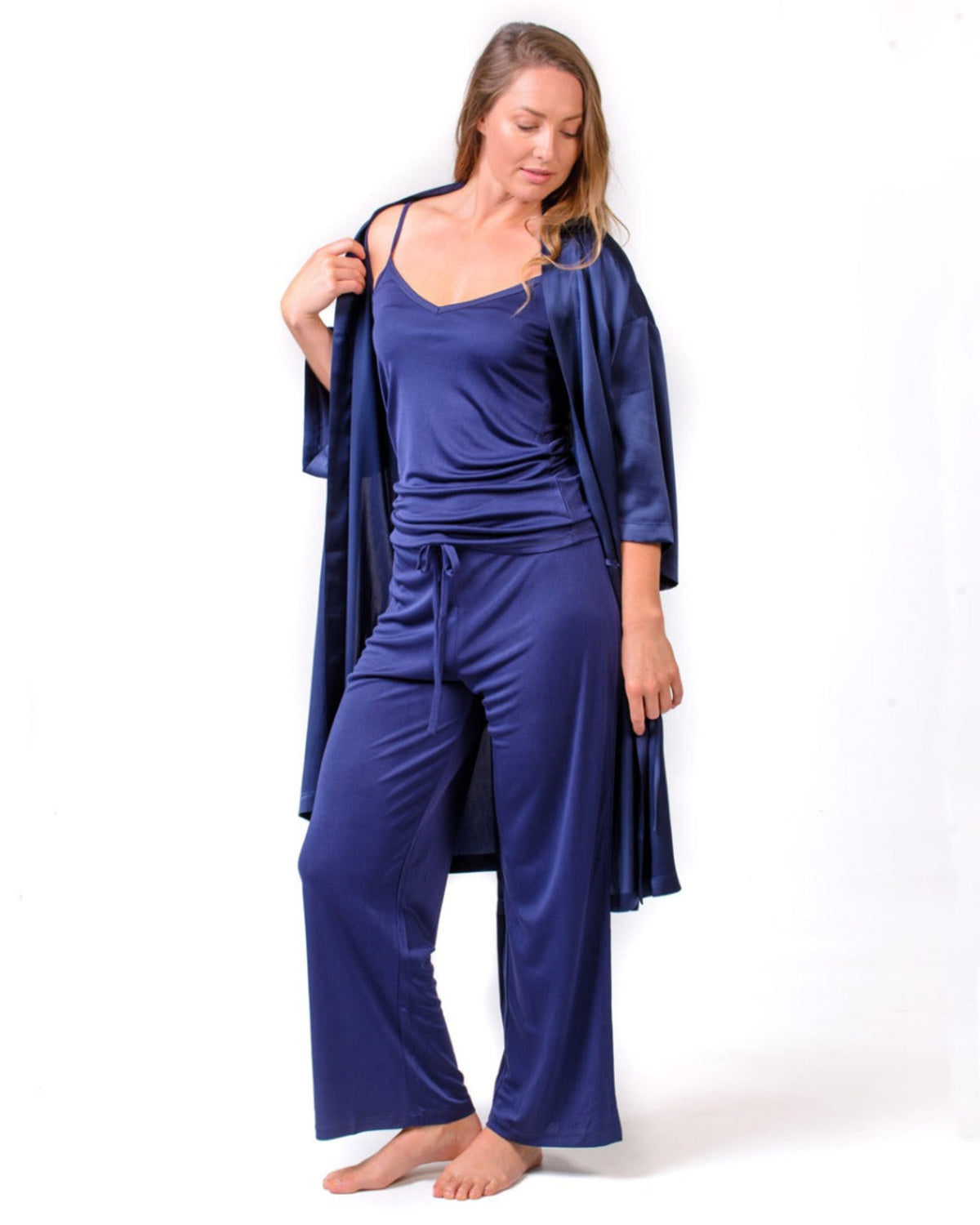Woman wearing a silk  blue satin loungewear set with a matching robe on a white background
