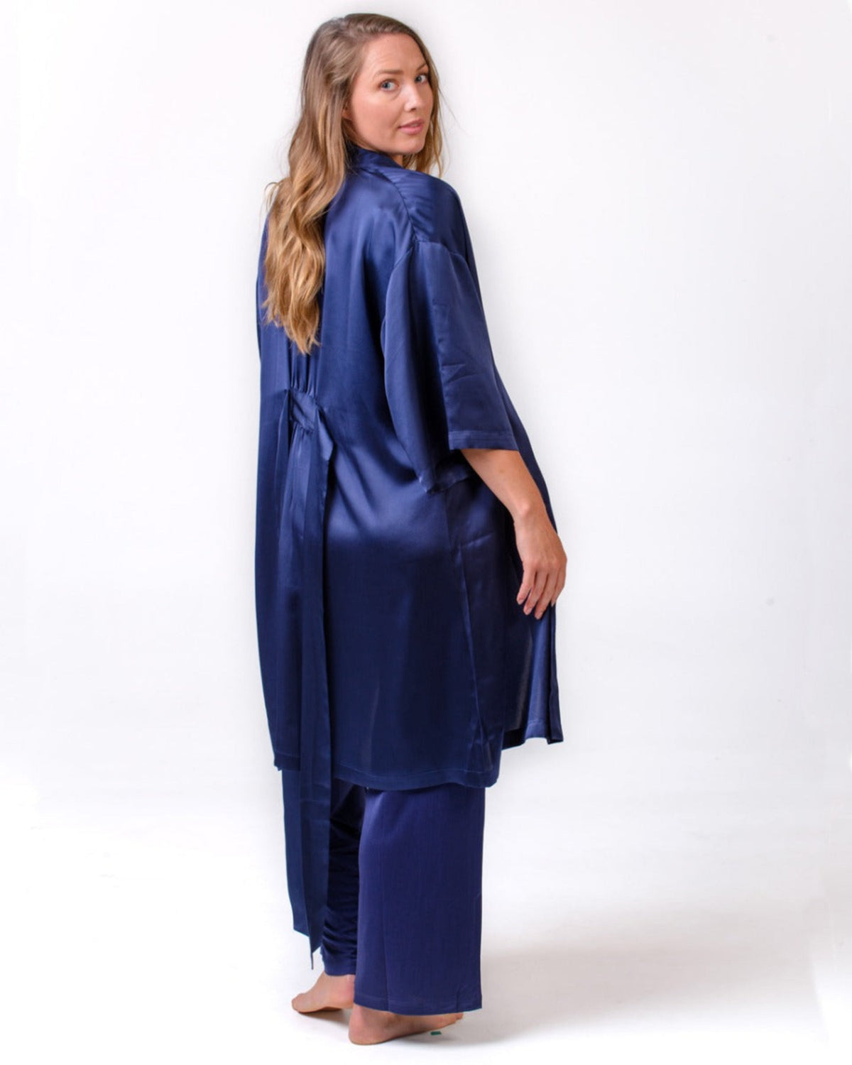 Woman wearing a silk  navy satin robe and pajama set on a