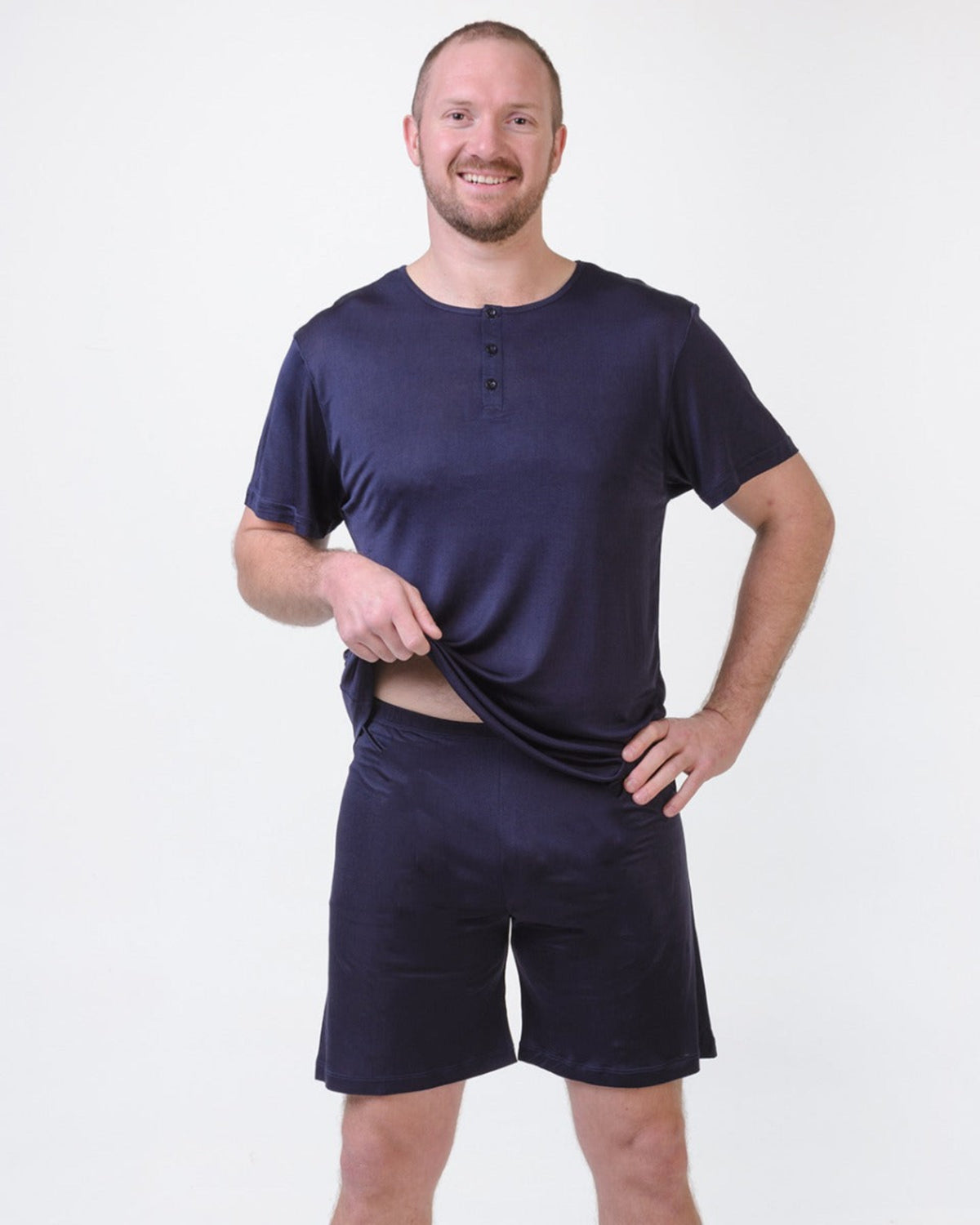 Man wearing a silk navy blue henley  top  and shorts on a white background