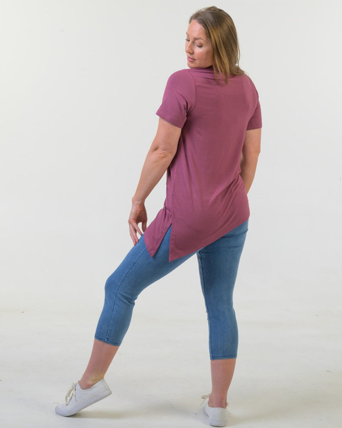 Woman wearing a bamboo tee shirt fmaroon tunic and blue leggings on a white background
