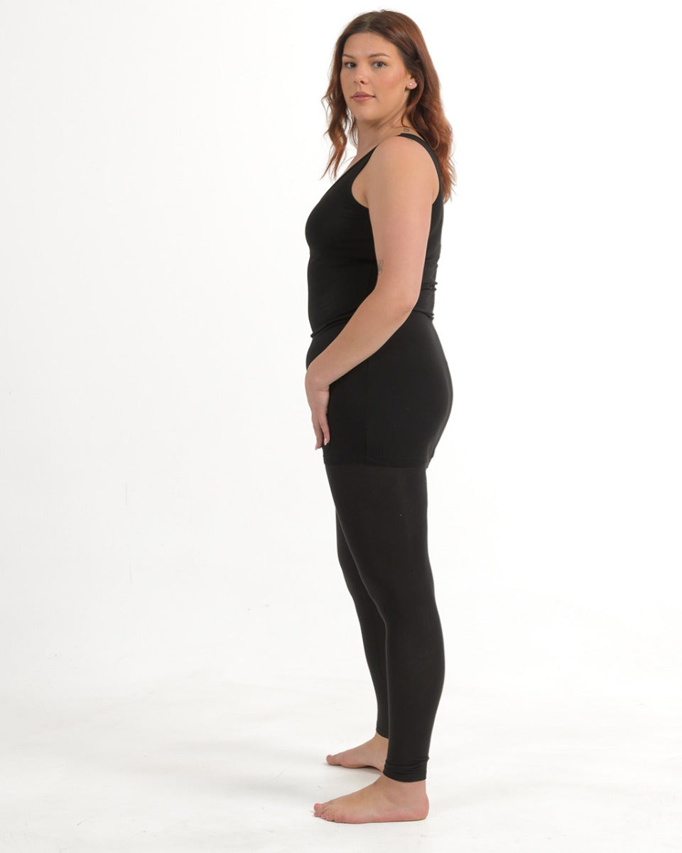 Woman wearing a black tank top and leggings on a white background