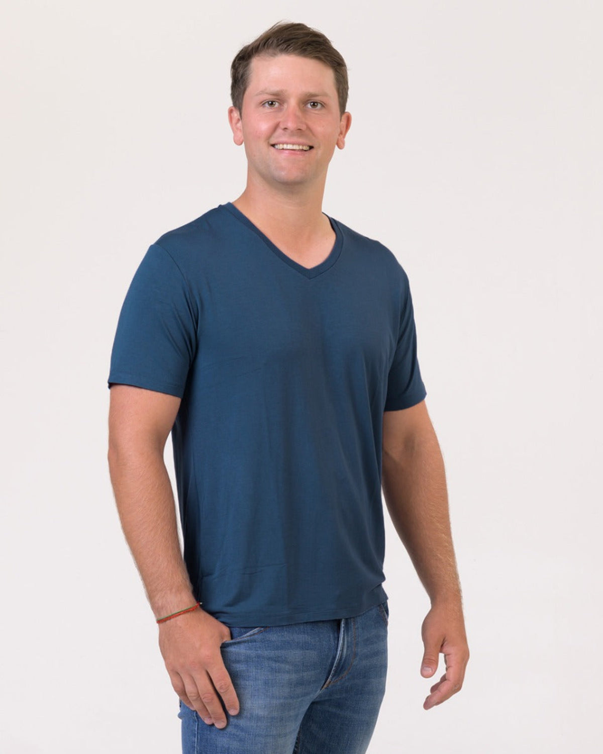 Man wearing a bamboo v neck blue t-shirt and jeans on a white background