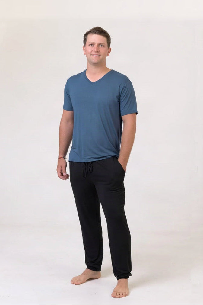 Man wearing a blue V-neck shirt and black pants on a white background