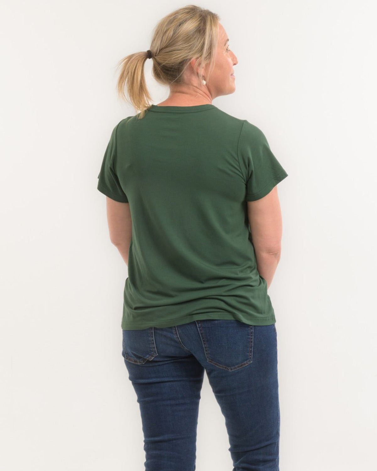 Person wearing a green t-shirt and blue jeans against a white background