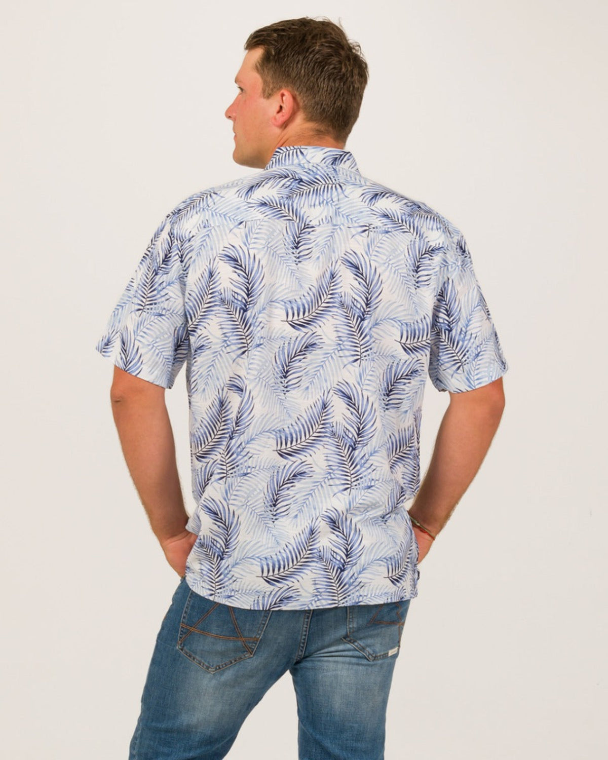 Man wearing a blue leaf patterned shirt on a white background