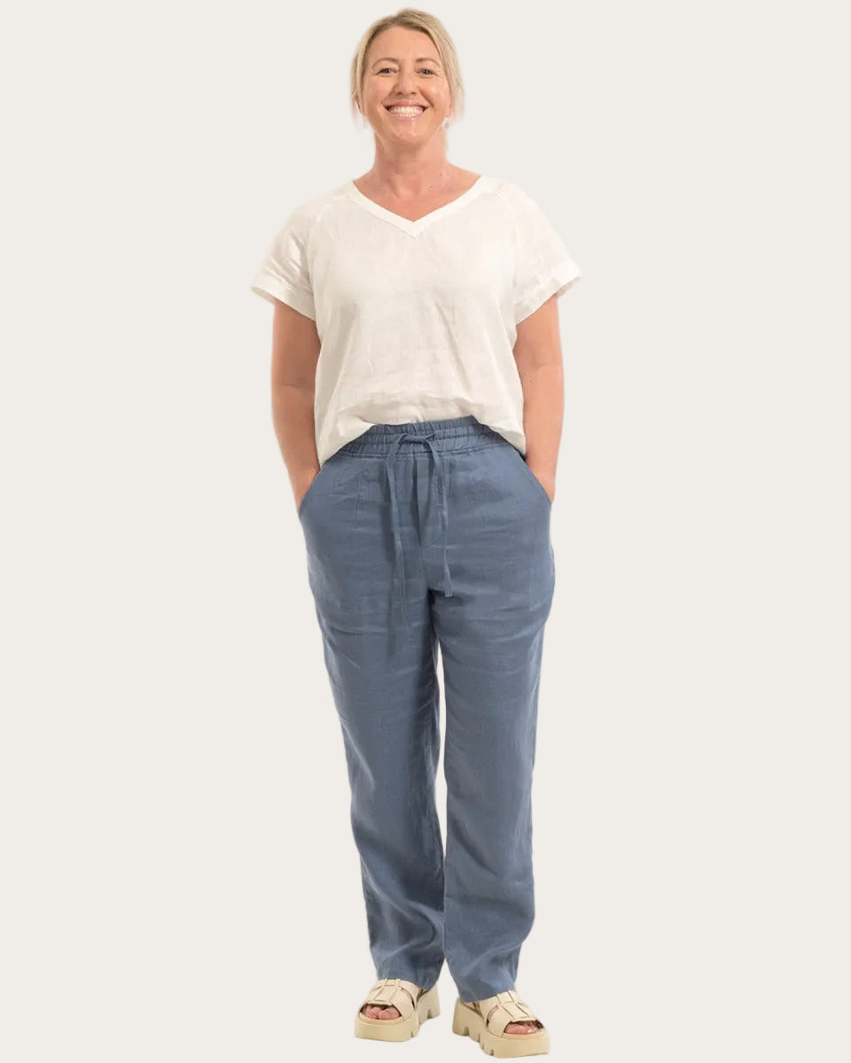 Woman wearing a white t-shirt and blue 100% hemp pants on a white background