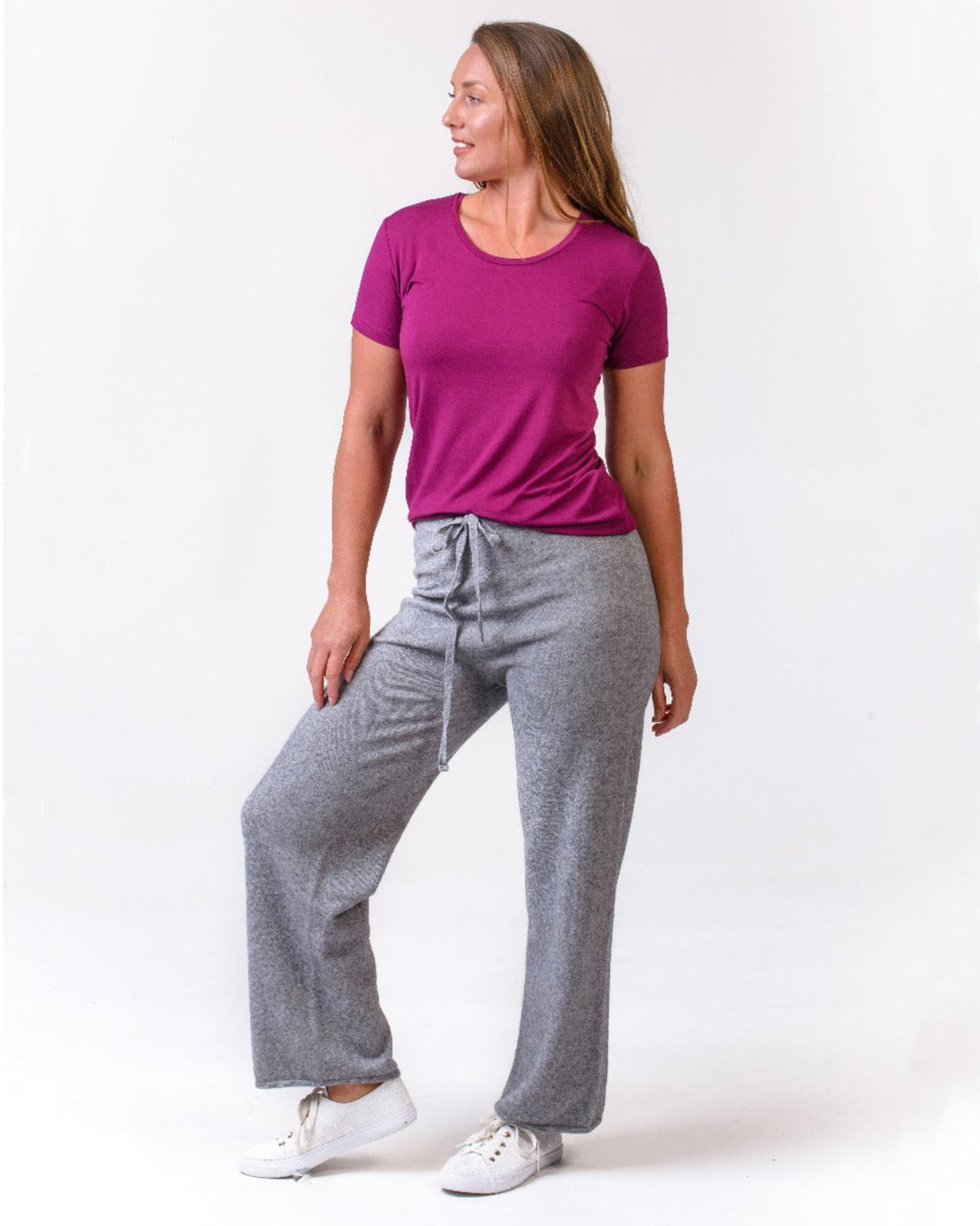 Possum Merino Woman wearing a purple shirt and gray pants on a white background