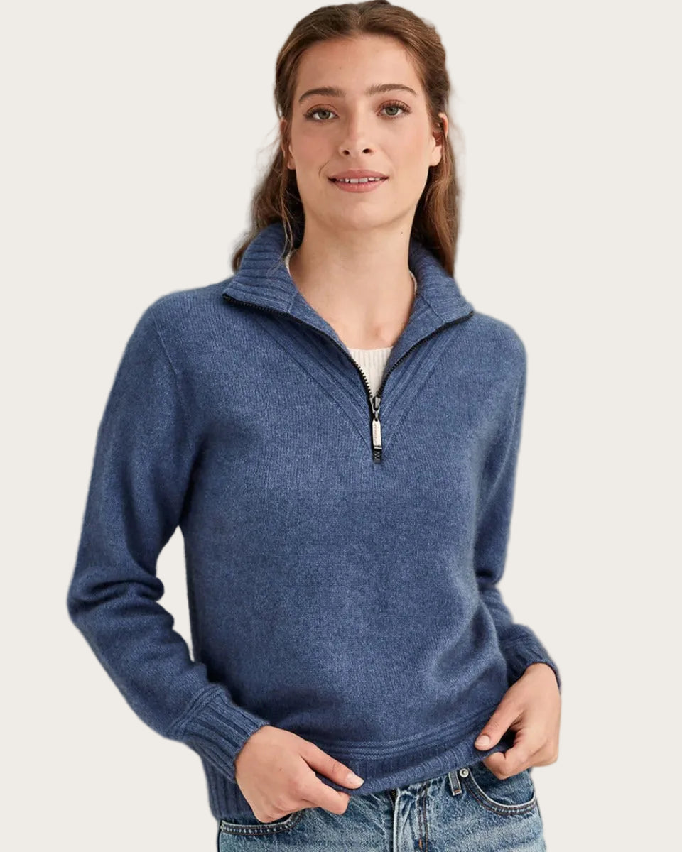 Woman wearing a blue pullover with a zipper on a gray background