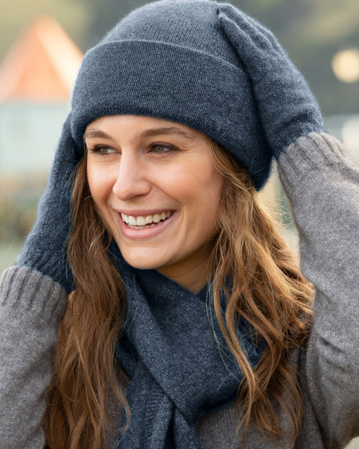 possum merino Woman wearing a blue knit hat and scarf, smiling outdoors.