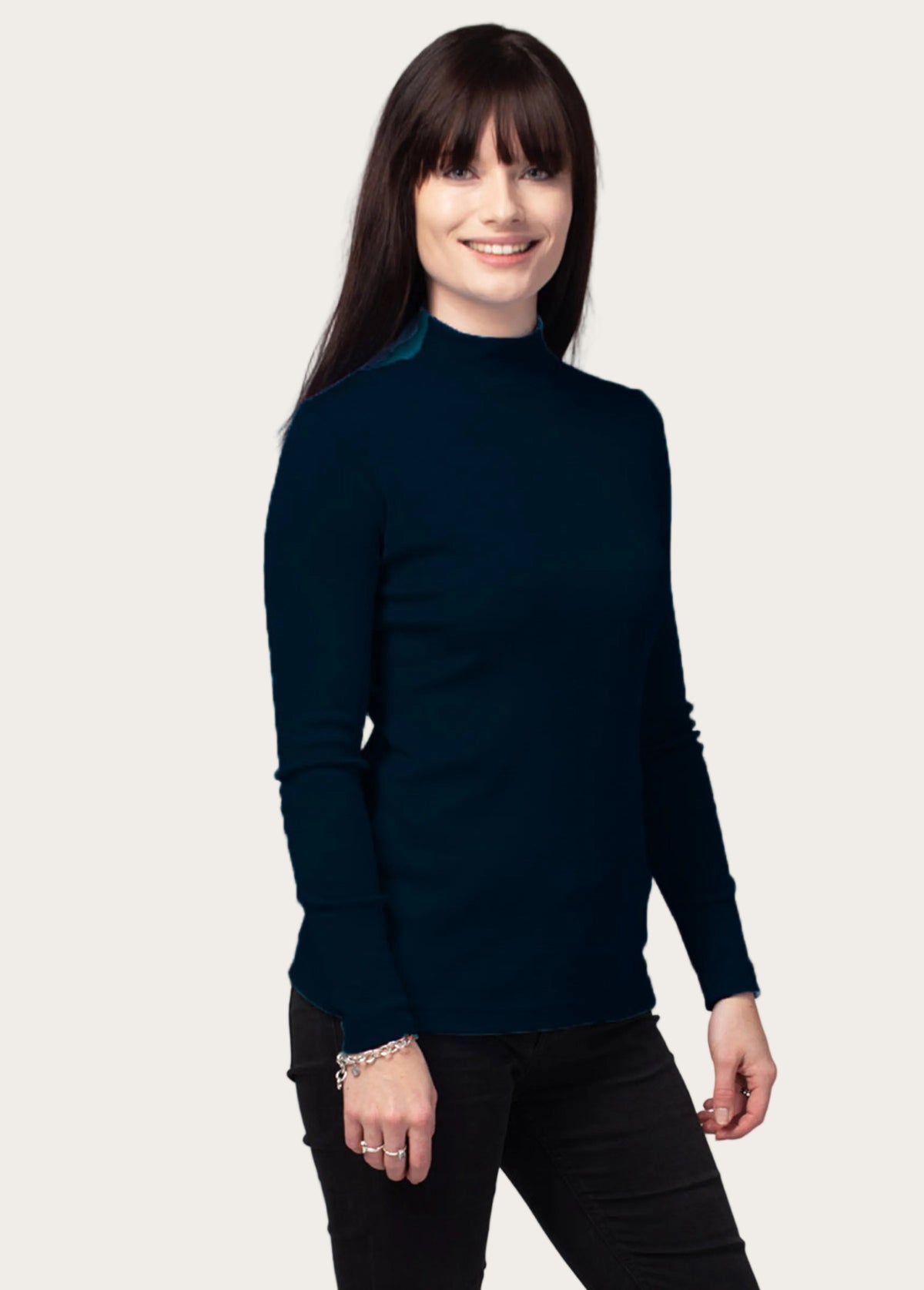 Woman wearing a merino dark blue turtleneck sweater against a gray background
