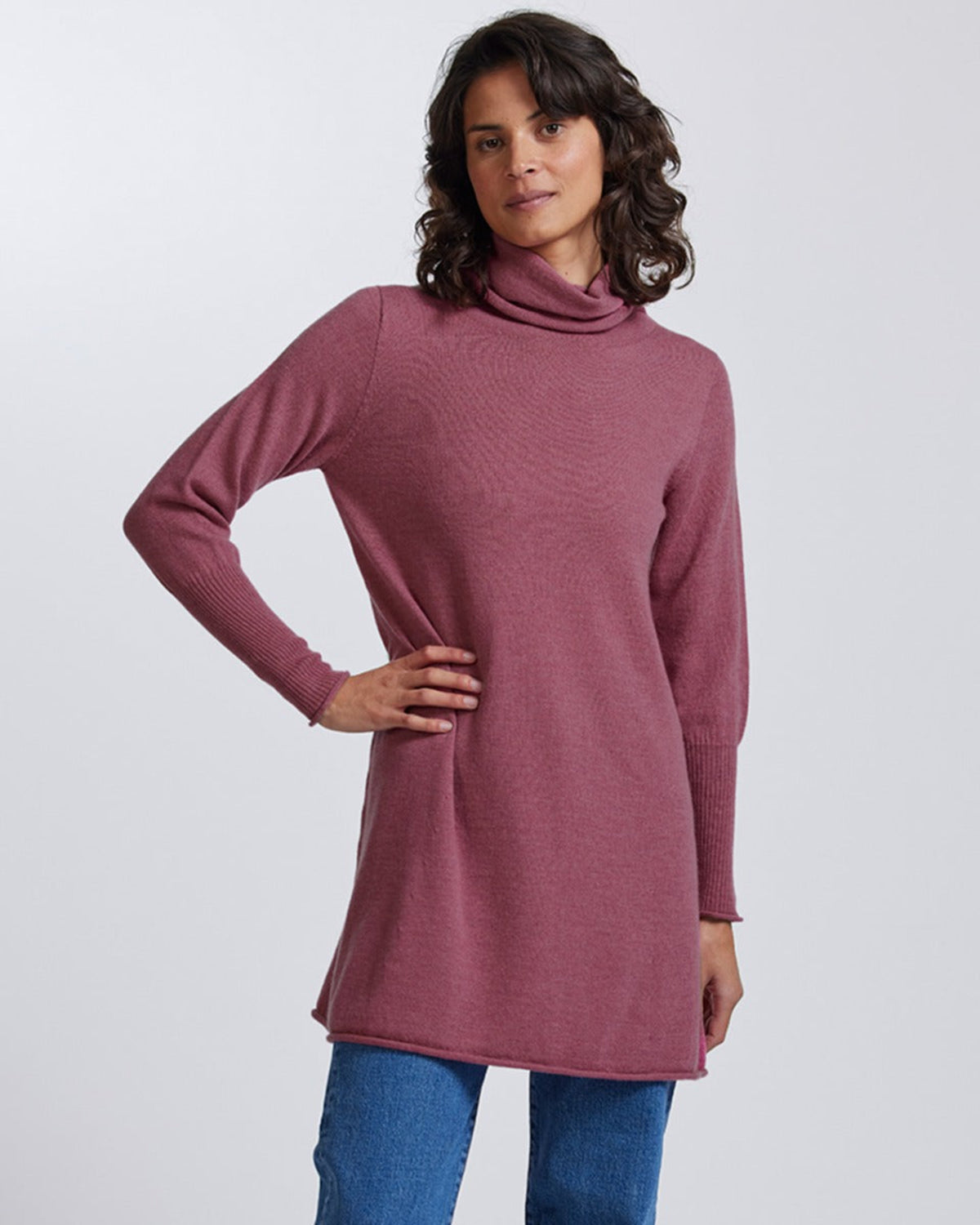 Woman wearing a merino mauve turtleneck sweater against a white background