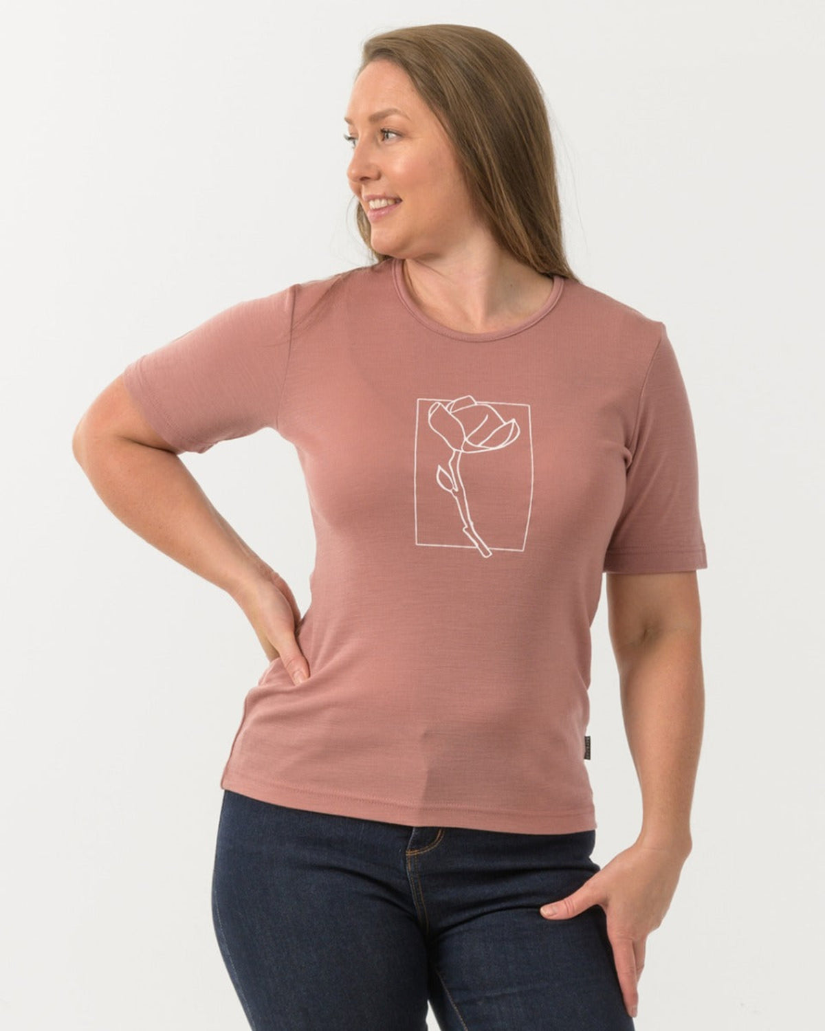 Woman wearing a merino blush t-shirt with a white graphic design on a plain background