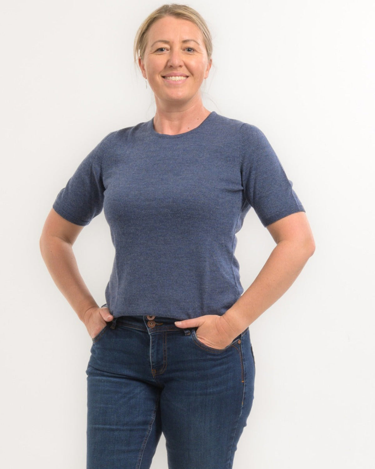 Person wearing a merino blue t-shirt and jeans against a white background