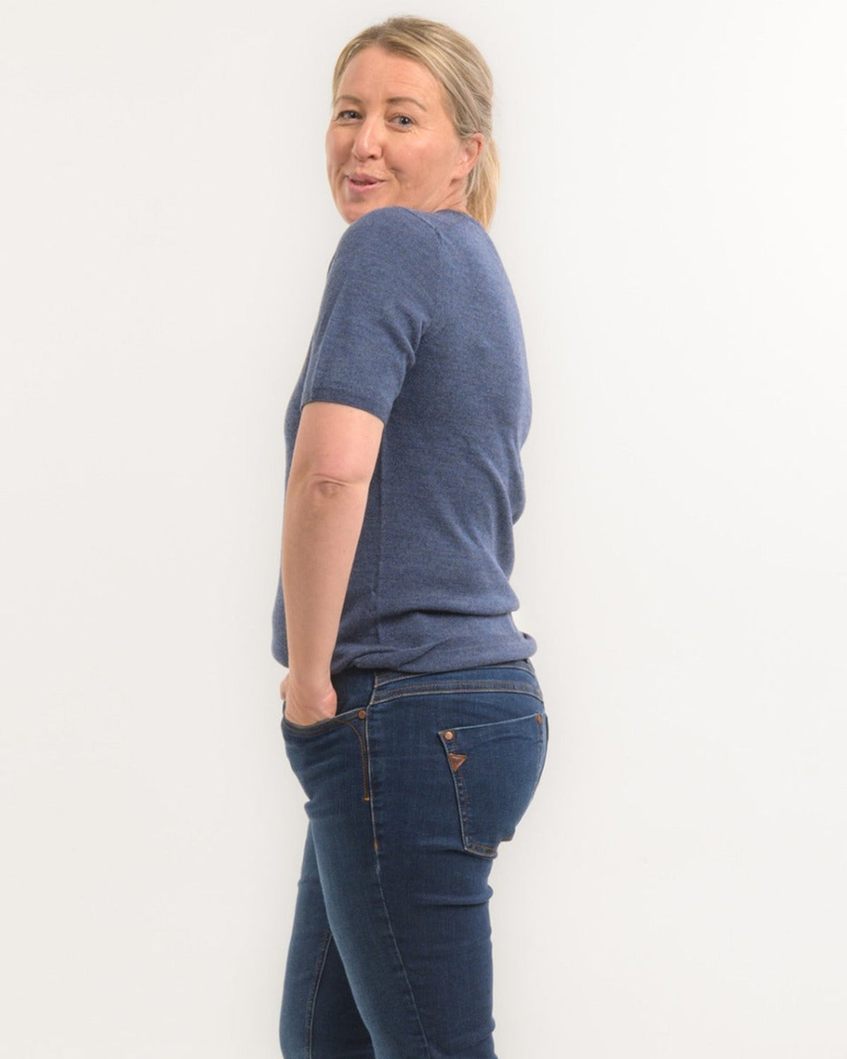 Woman wearing a merino blue t-shirt and jeans against a white background