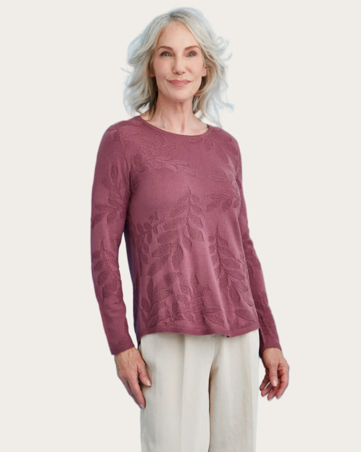 Woman wearing a merino mauve sweater against a blue background