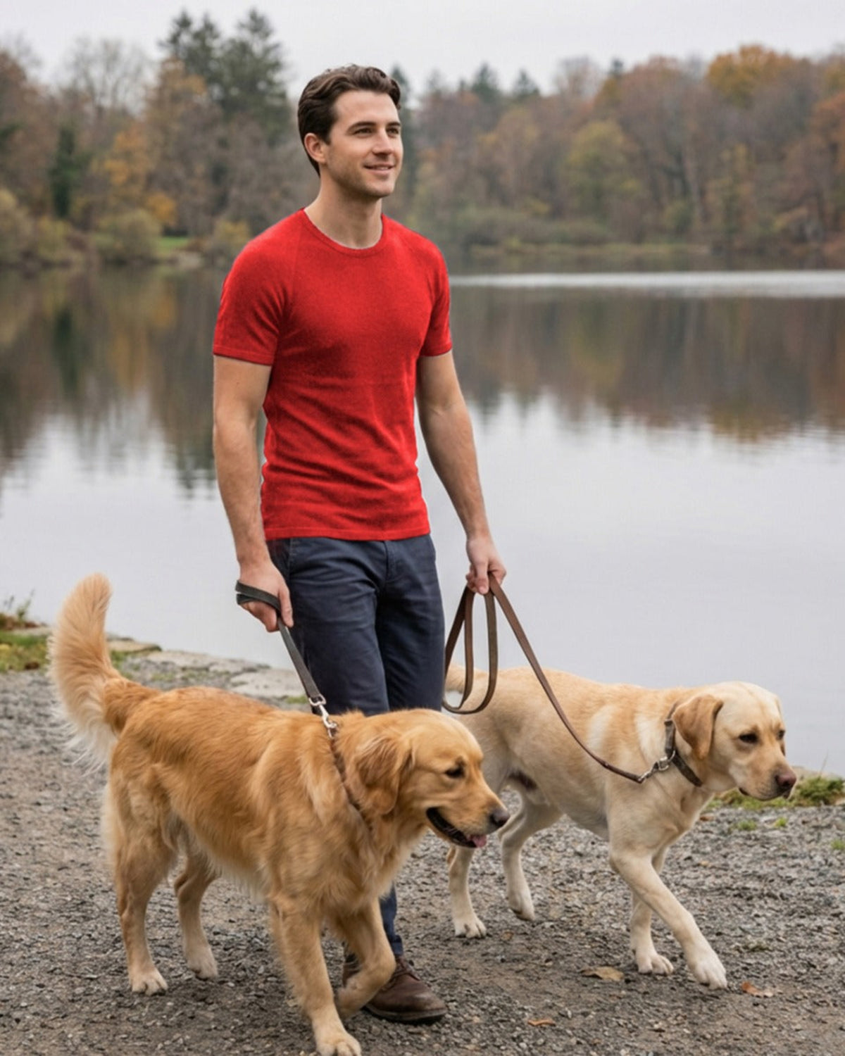 Man in a merino red shirt walking two dogs by a lake