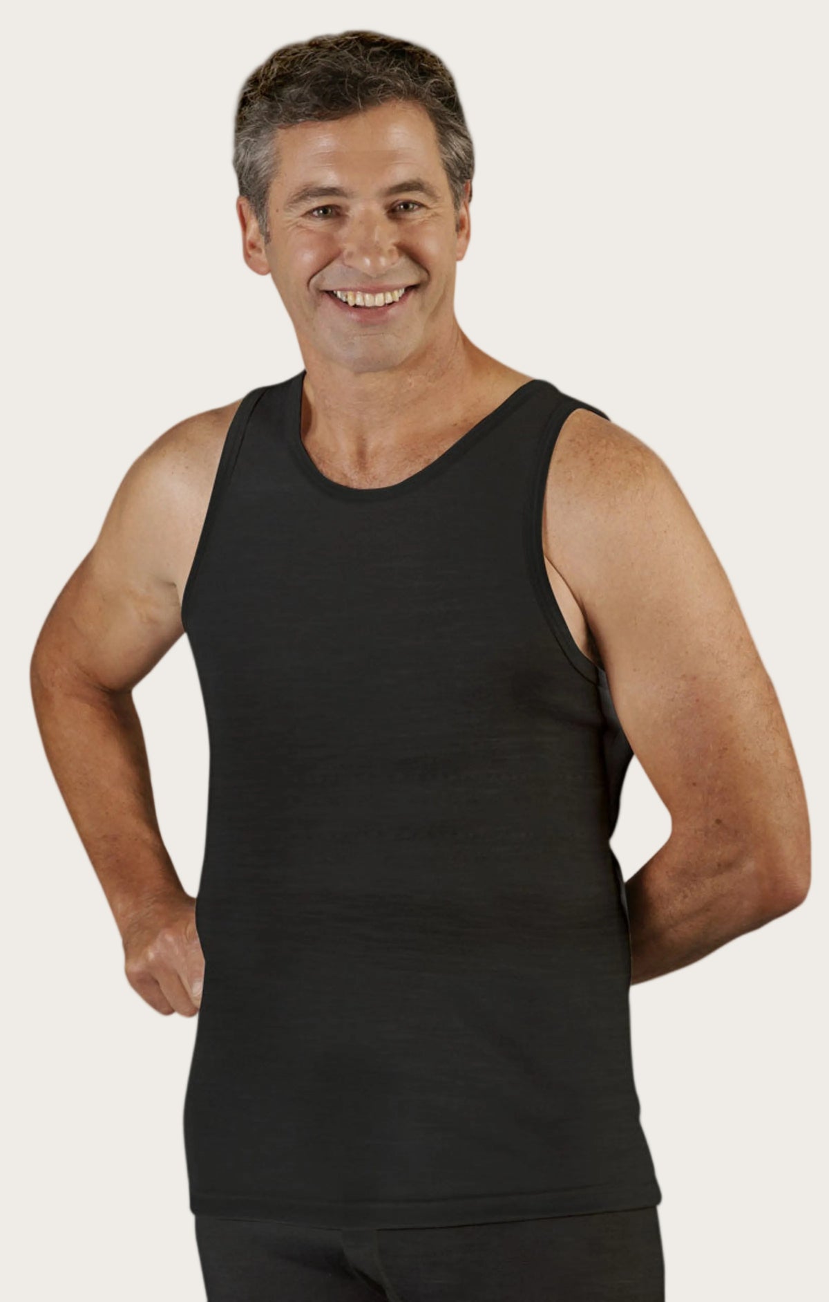 Man wearing a superfine merino black tank top on a white background