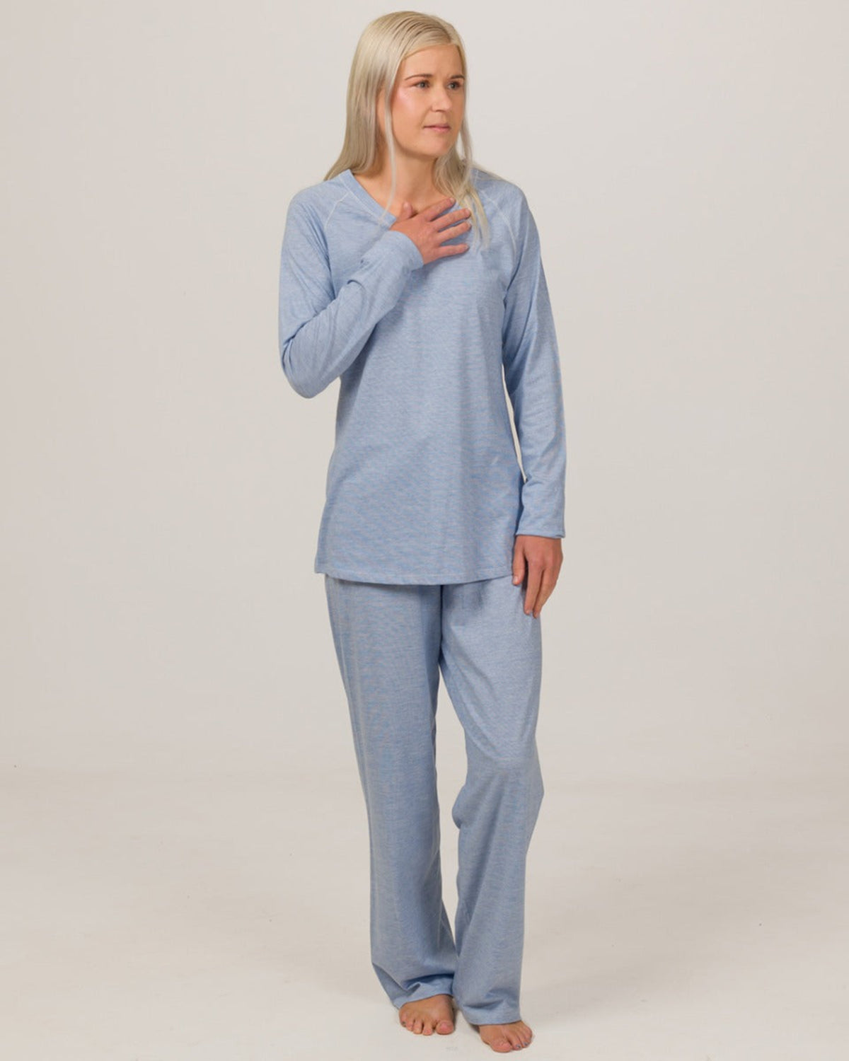 Woman wearing a merino cotton  blue pajama set against a plain background