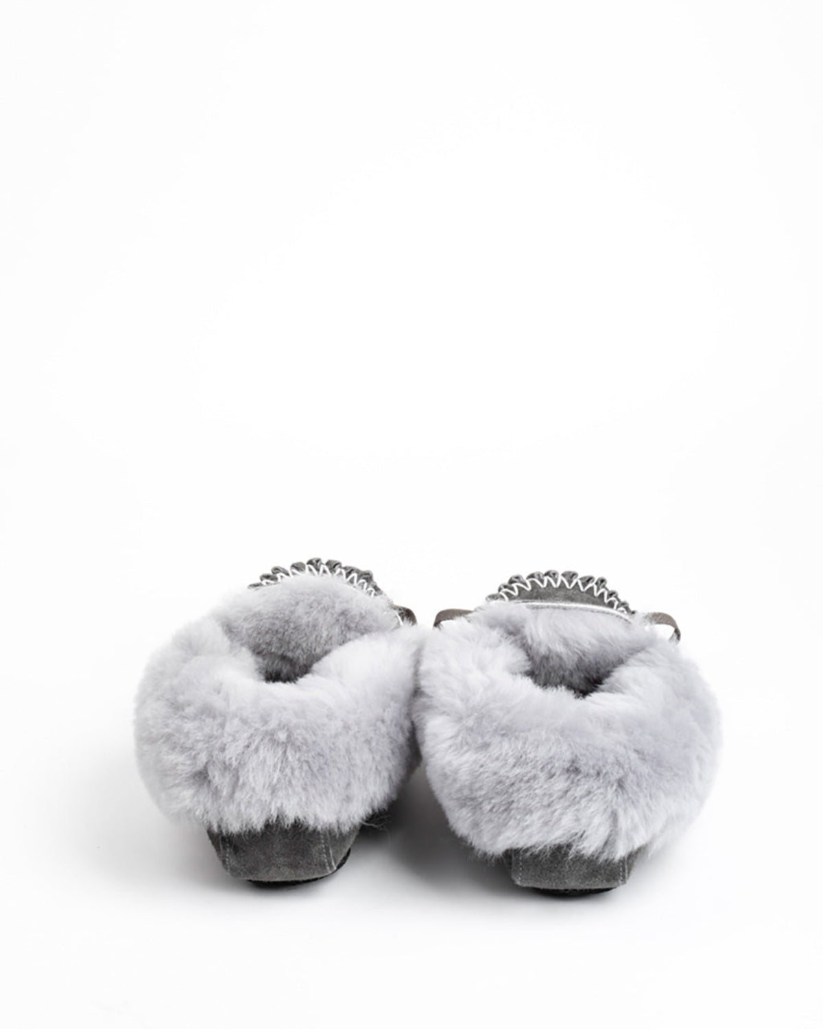 A pair of fluffy light gray sheepskin slippers with metallic silver chain detailing across the top, shown from the back on a white background.