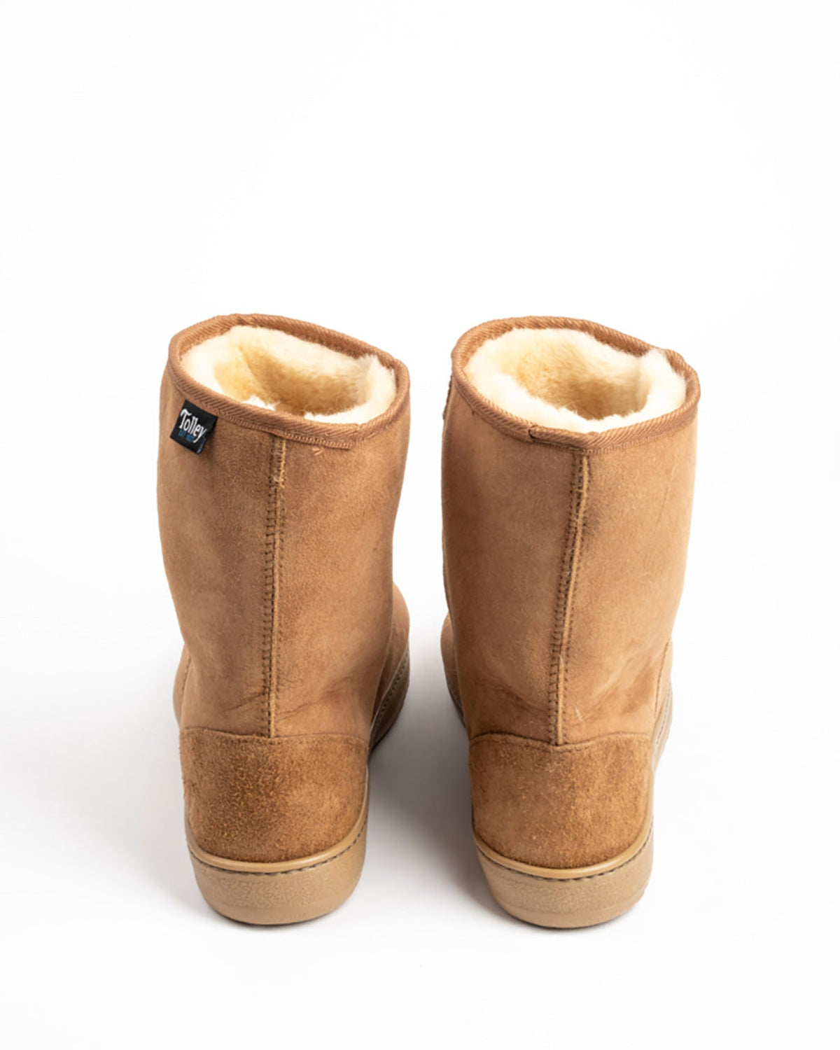 A pair of tan suede mid-calf boots with a cream shearling lining, shown from the back against a plain white background.