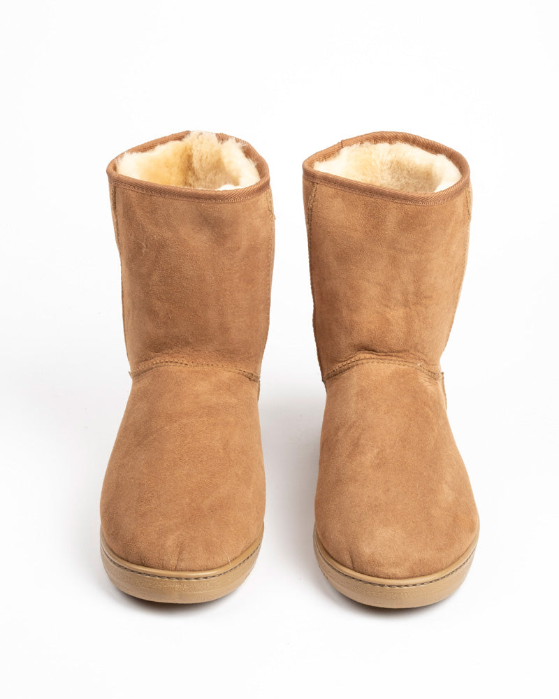 A pair of mid-calf suede boots in a warm tan color, featuring a soft cream-colored shearling lining visible at the collar, set against a plain white background.