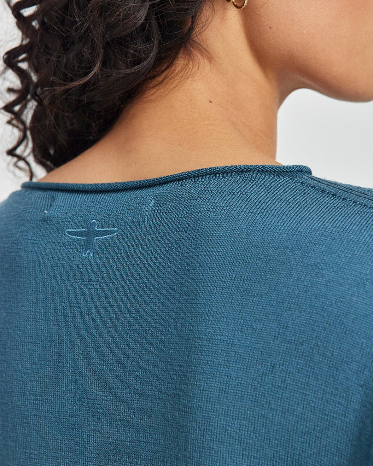 Close-up of a person merino wearing a blue sweater with a brand logo on a white background