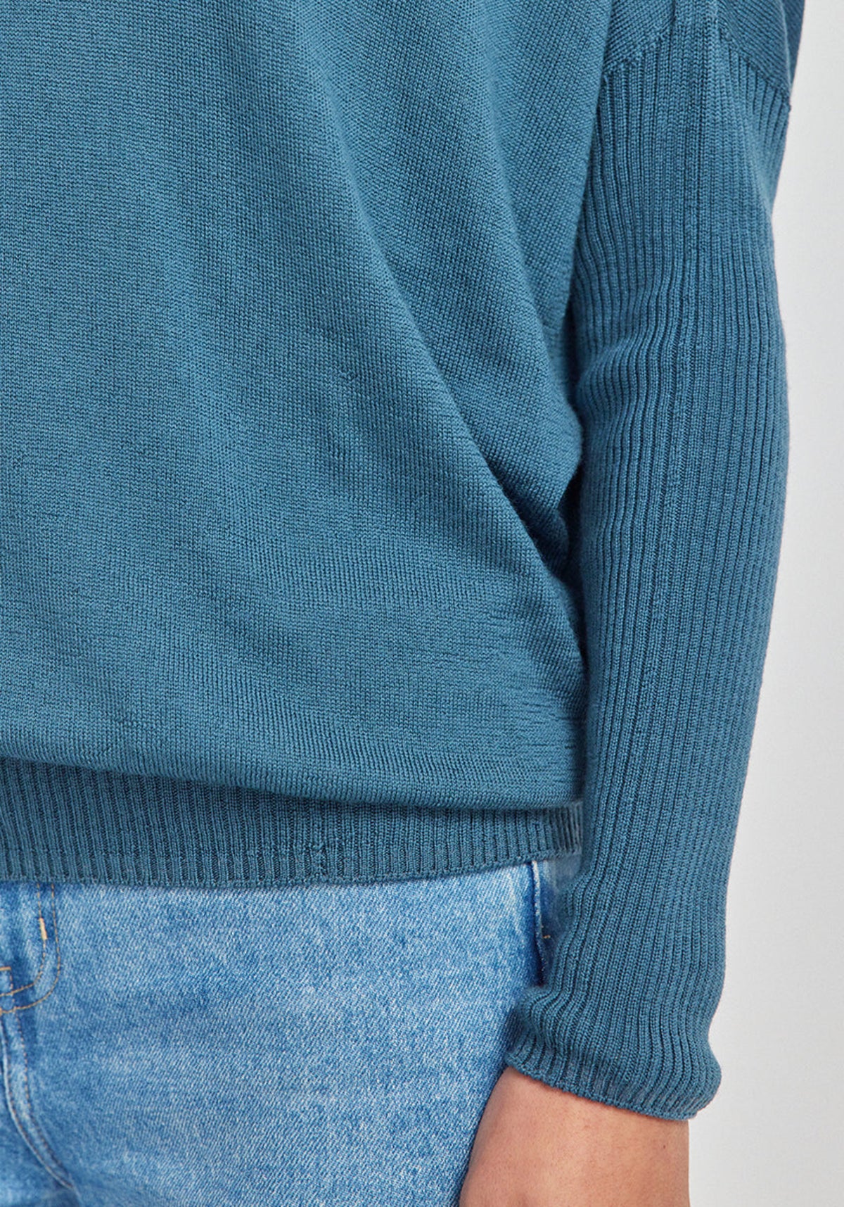Teal sweater merino worn by a person on a light gray background