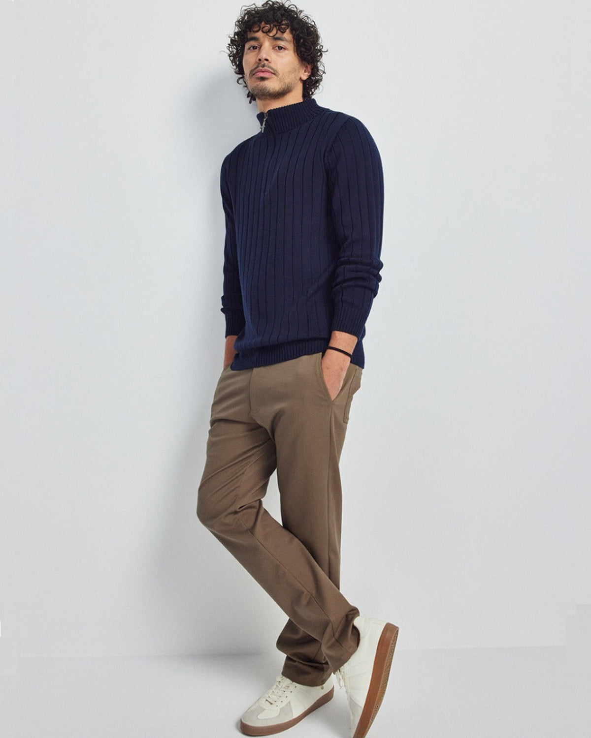 Man wearing a merino navy sweater and brown pants against a white background