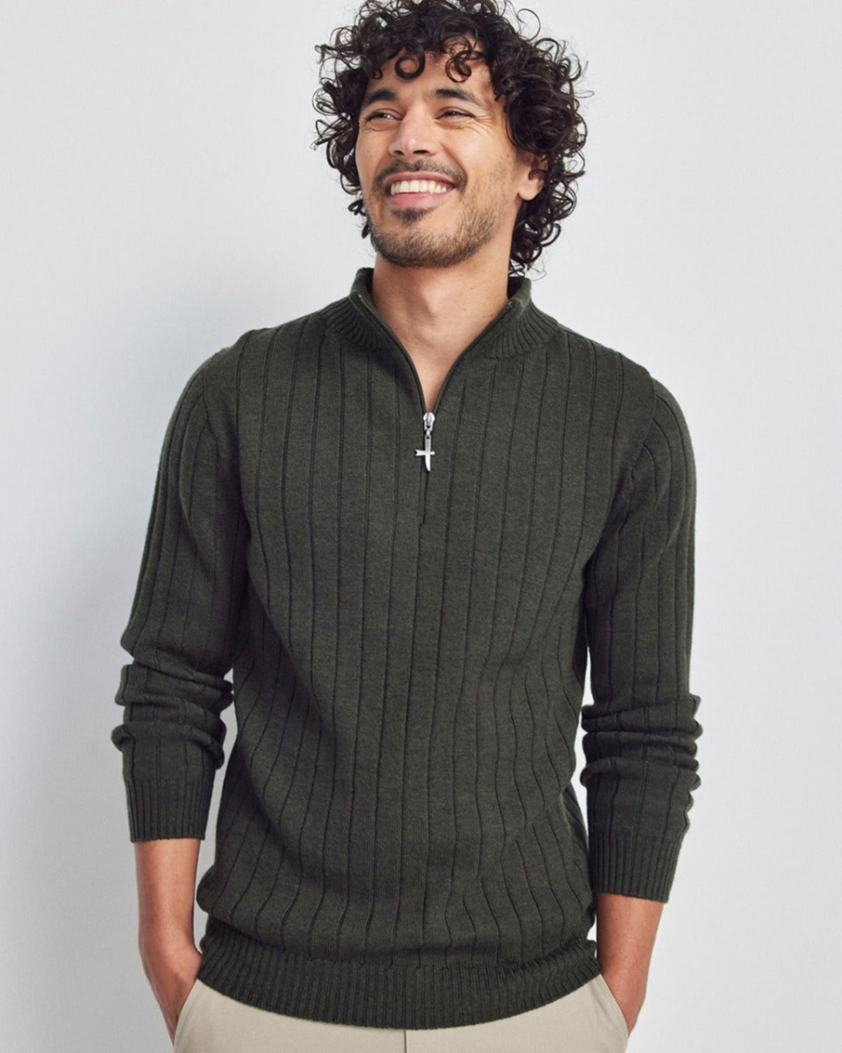 Man wearing a merino dark green sweater with a zipper on a light gray background