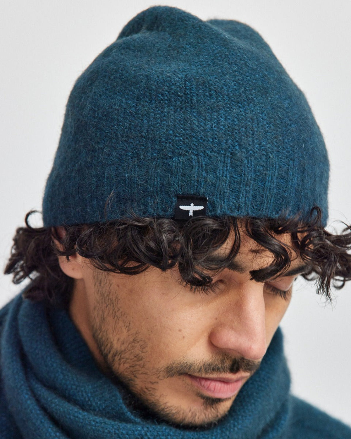 Possum Merino Person wearing a blue beanie and scarf against a white background