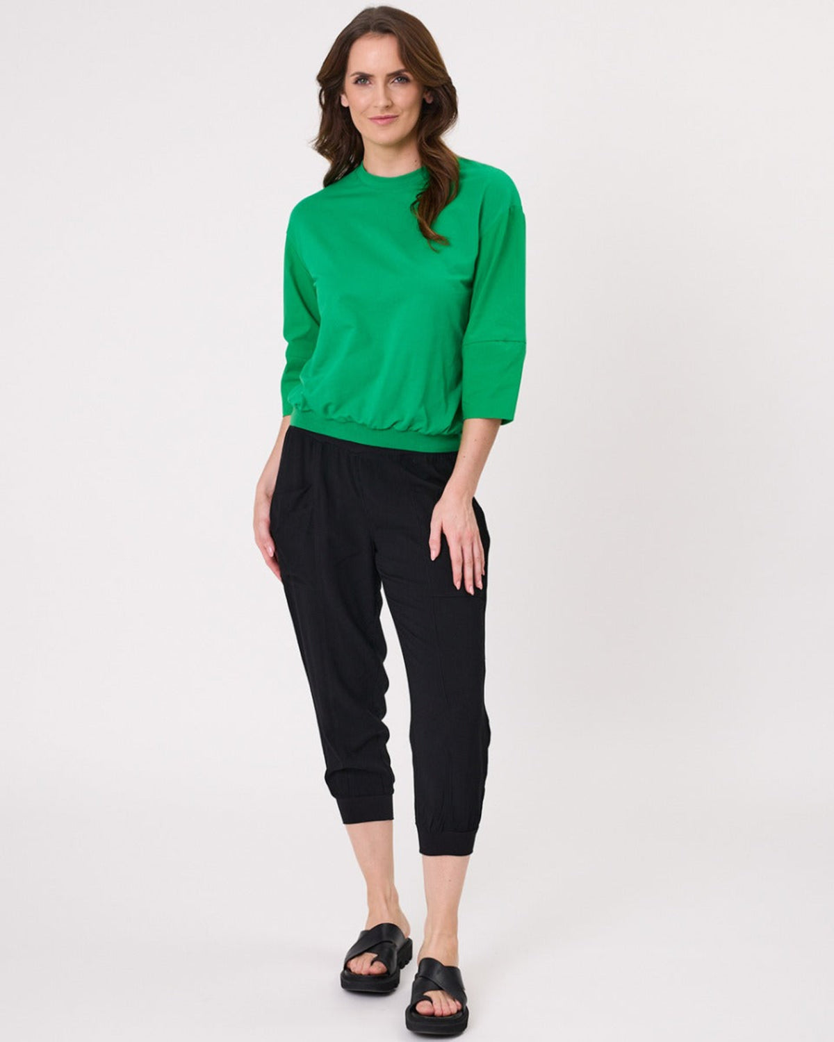 Viscoe Woman wearing a green sweater and black pants on a white background