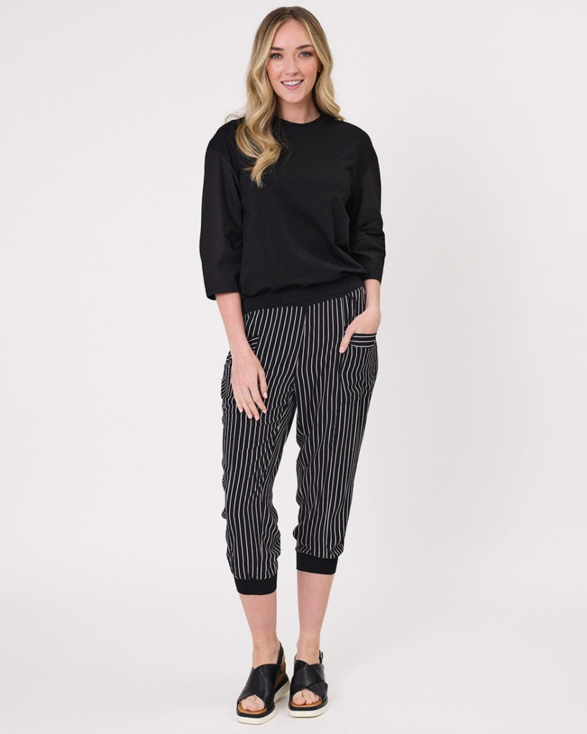 Viscoe Woman wearing a black top and striped pants on a white background
