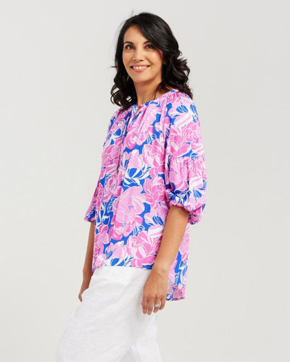 Woman wearing a pink floral blouse against a white background