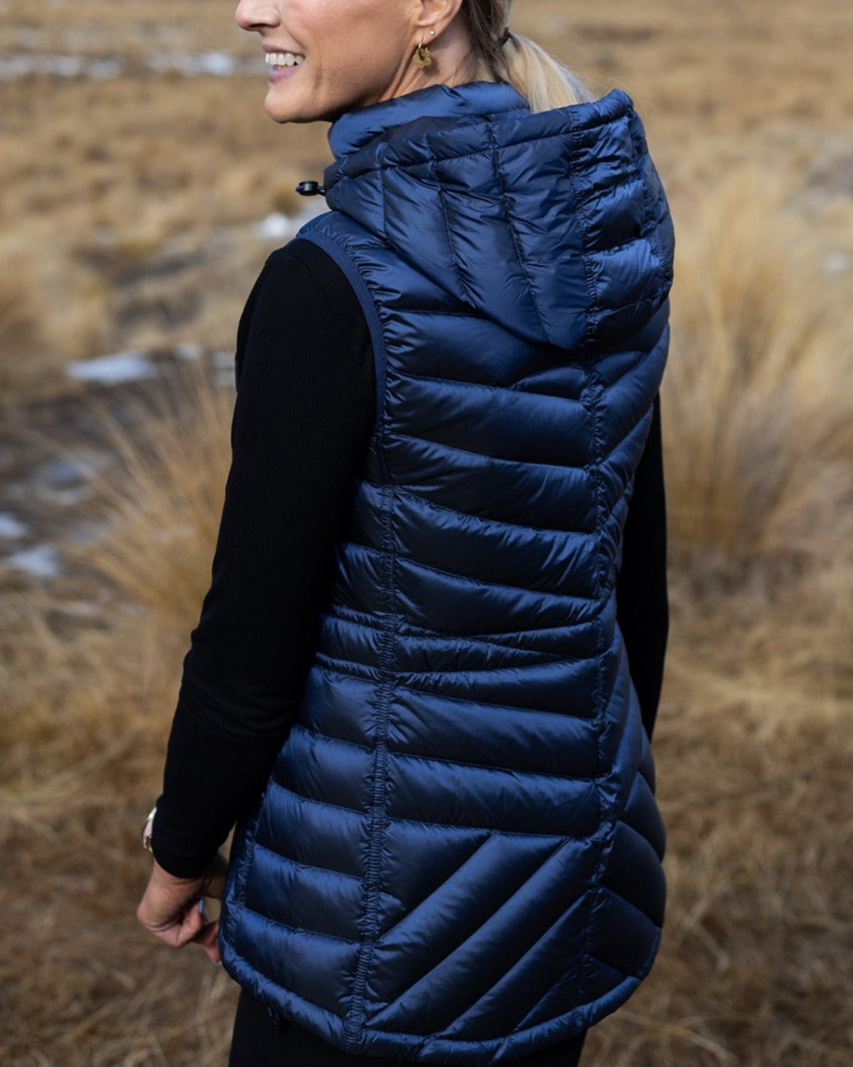 Person wearing a blue puffer vest in a natural setting