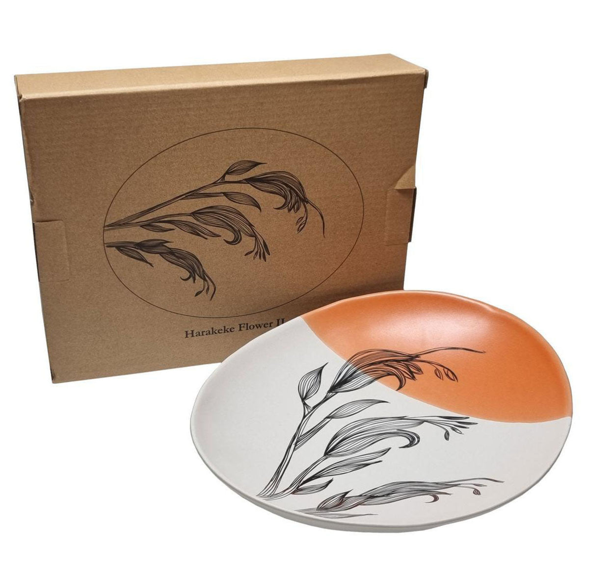 Ceramic plate with floral design and orange accent next to a brown box with similar design.