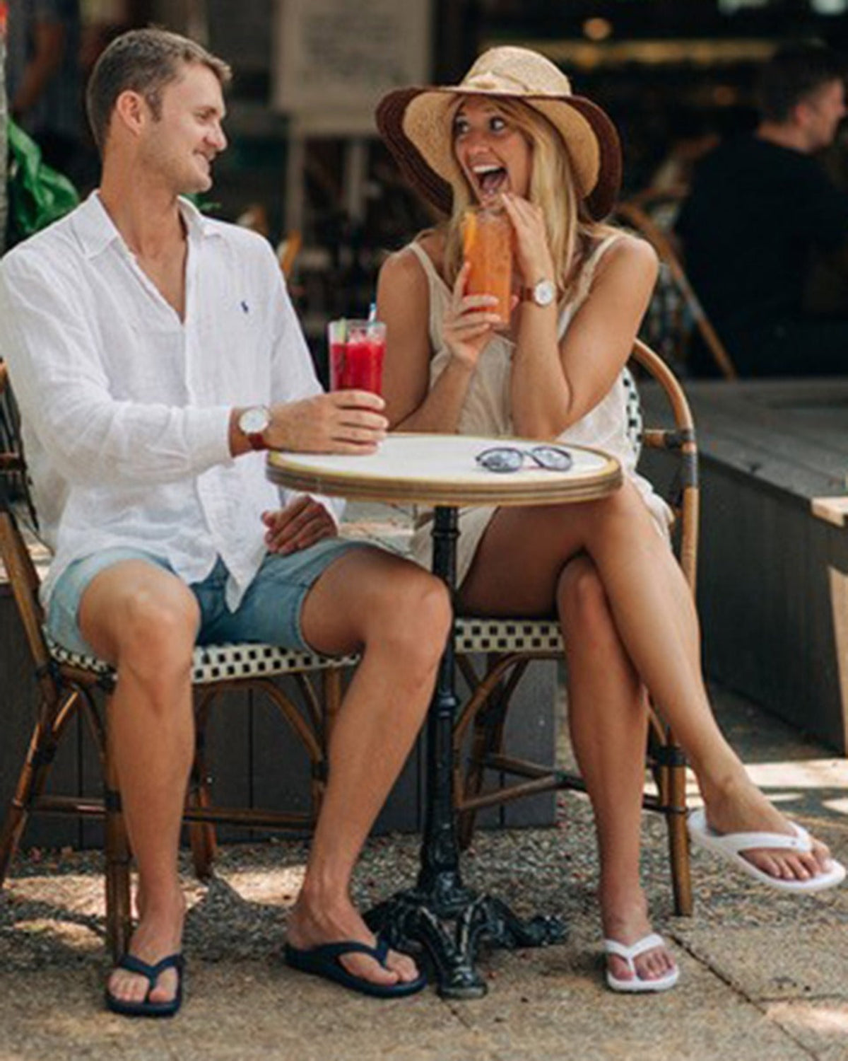 Jandals Man and woman sitting at a table outdoors, enjoying drinks.