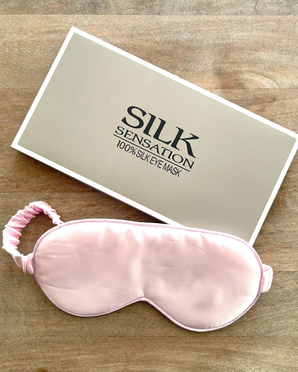 Silk sensation 100% silk eye mask with packaging on a wooden surface