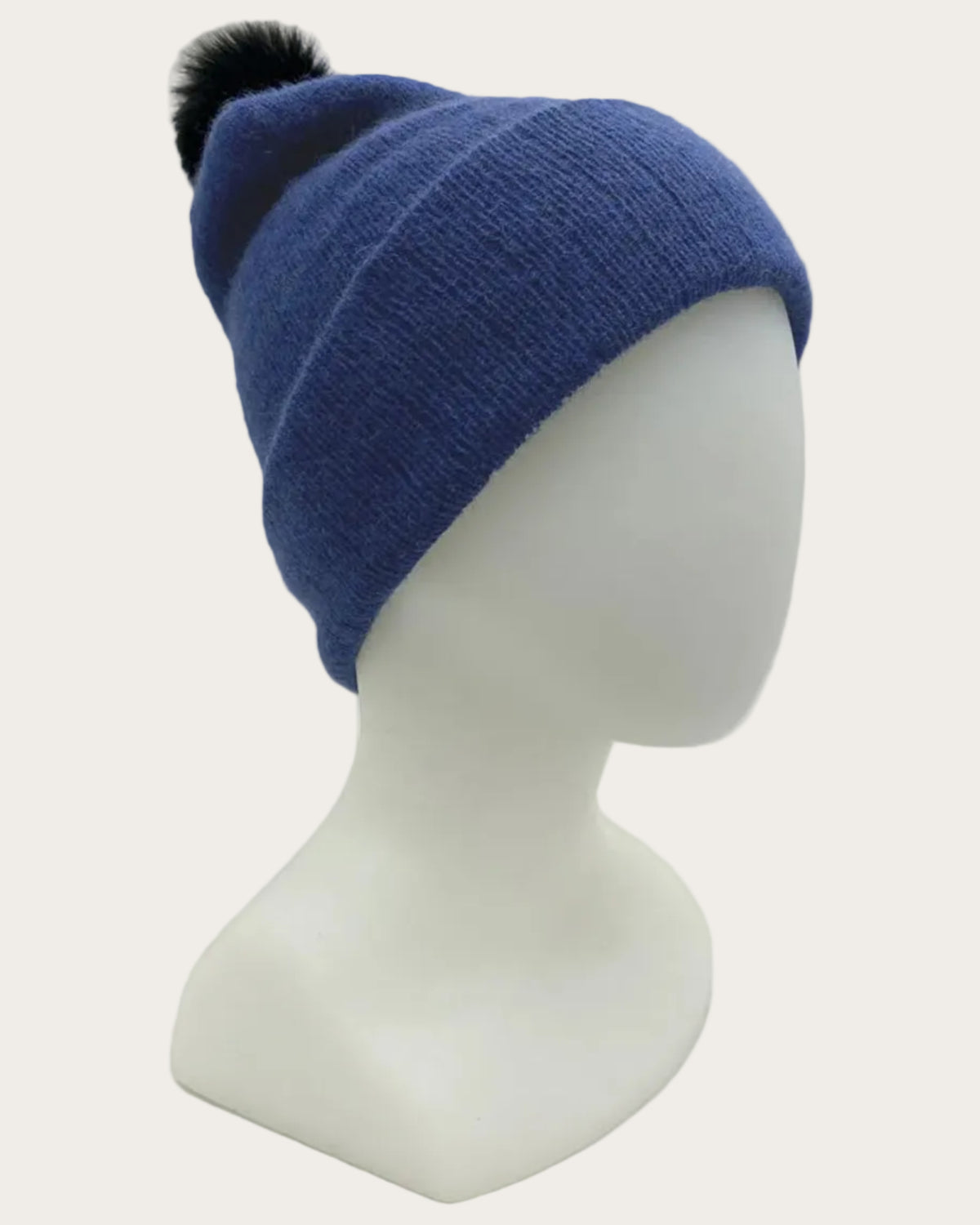 Blue possum merino beanie with a black pom-pom on a mannequin head against a white background