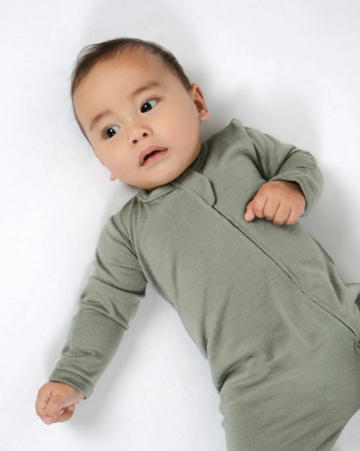 Merino Baby wearing a green onesie on a white background