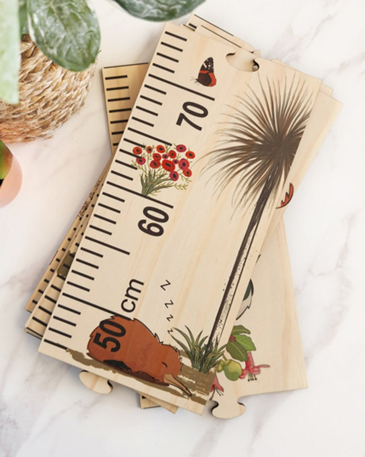 Wooden growth chart with illustrations on a white surface