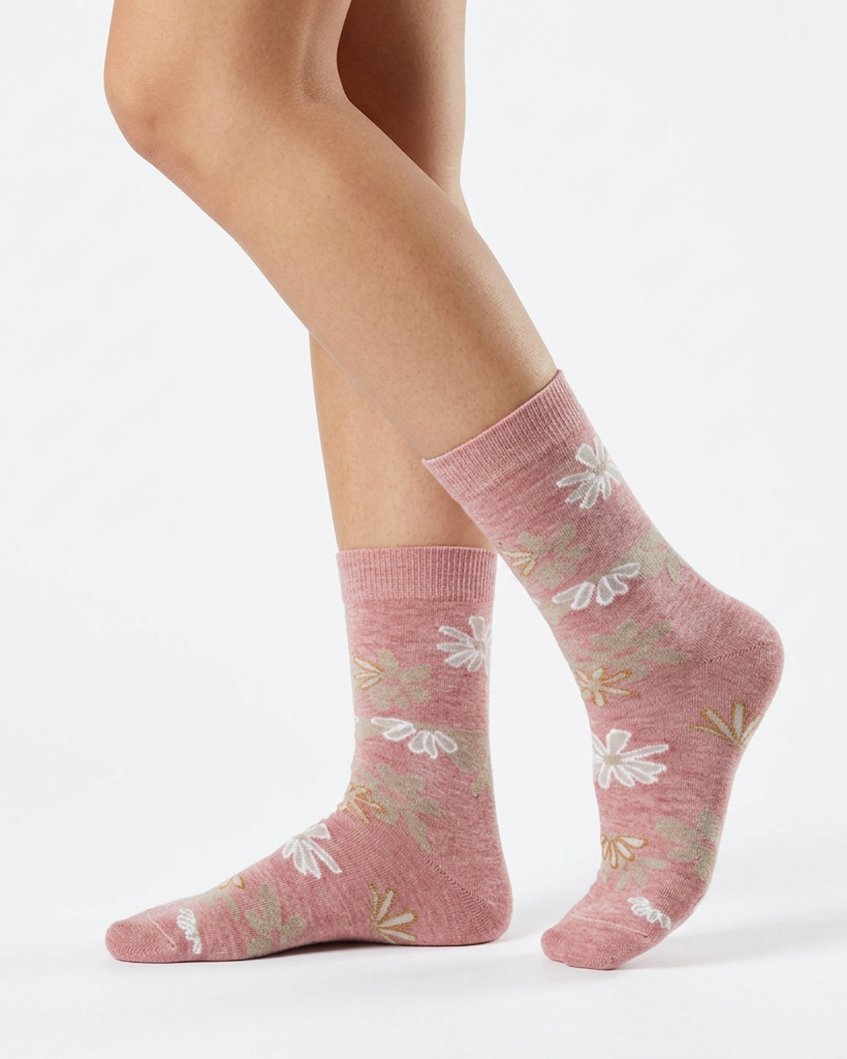 A pair of heathered dusty pink crew socks with a white and sage green floral pattern, shown on a model's feet against a clean white background.