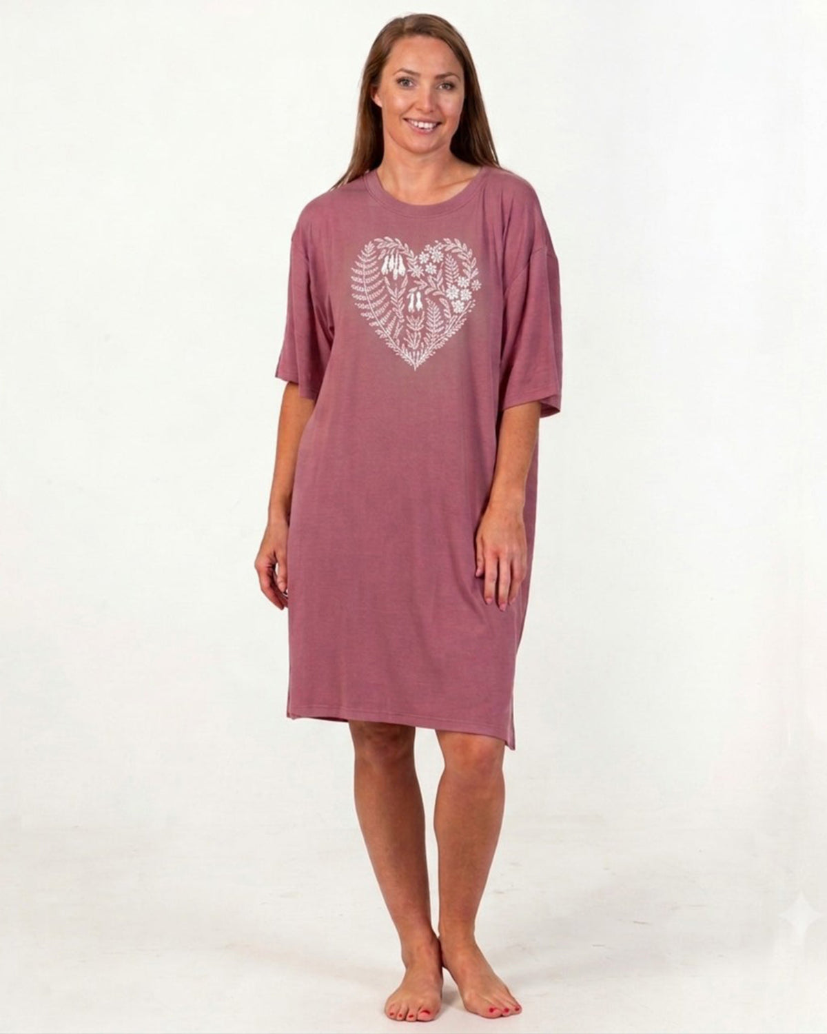 bamboo A woman modeling a dusty rose short-sleeve nightshirt with a white fern and bird heart graphic on the chest, standing against a plain white studio background.